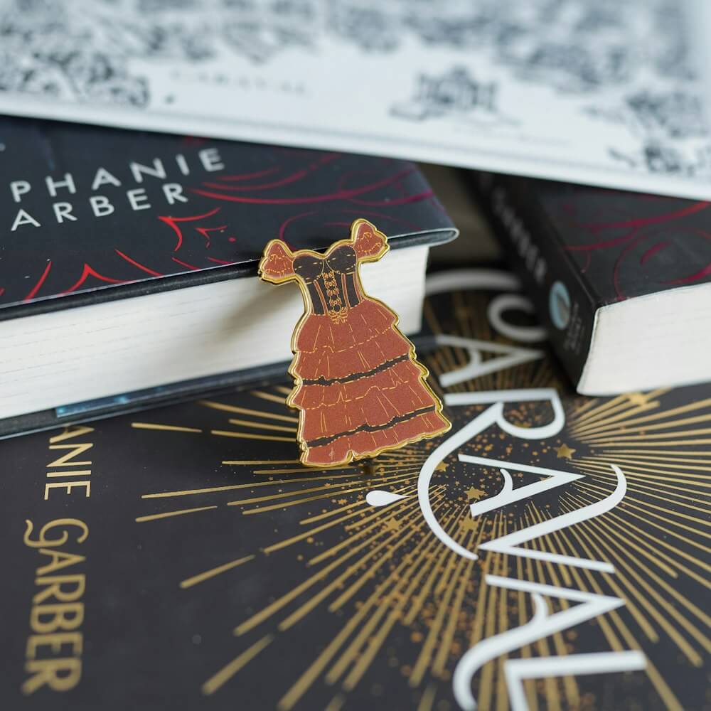 Caraval Lenticular Dress Pin has a gold edge and changes from white to a deep red dress with ruffles and black detailing.