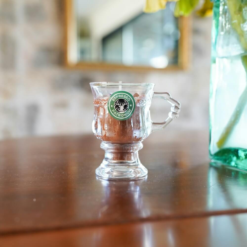 Espresso Patronum Candle shaped like a wizard pub glass with a coffee logo sticker and candle wax inside that looks like coffee foam.
