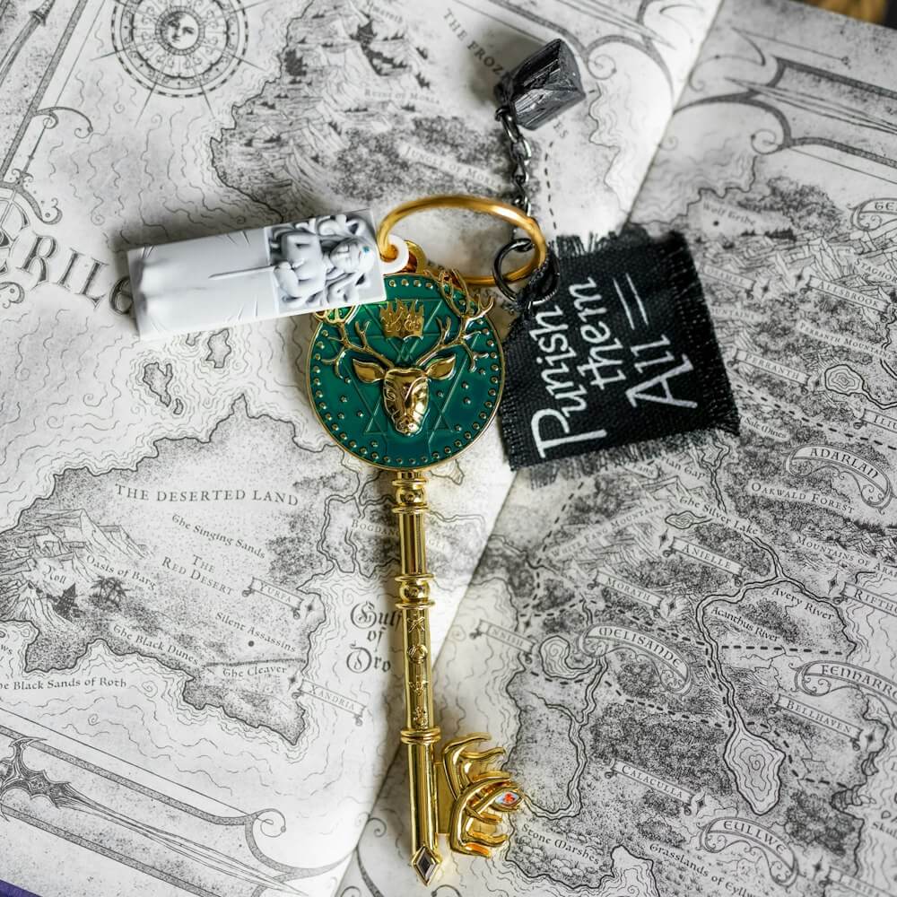 Sarah J. Maas Throne of Glass Key with a design of an amulet, a piece of cloth, a black rock, and Elena's sarcophagus
