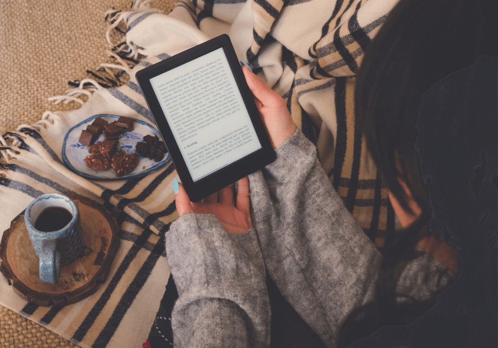 A woman holding an E-book with digital reading and cozy snacks