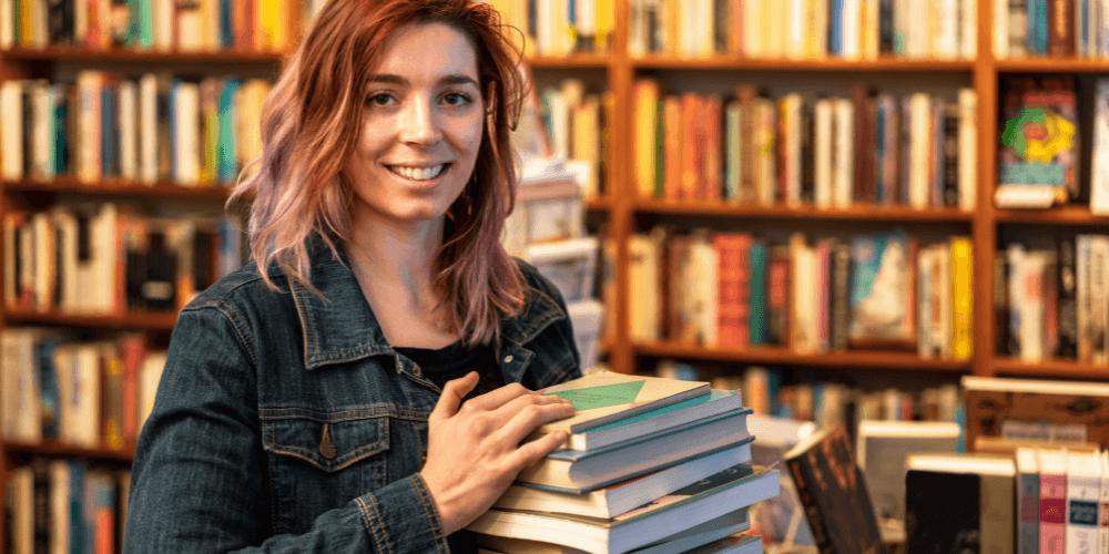 girl holding a stack of book working at a library