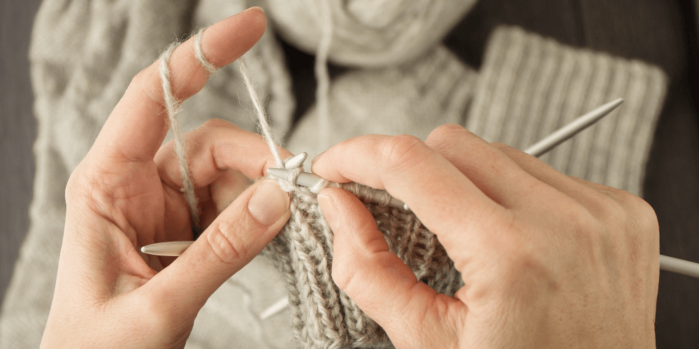 hands knitting with grayish beige yarn