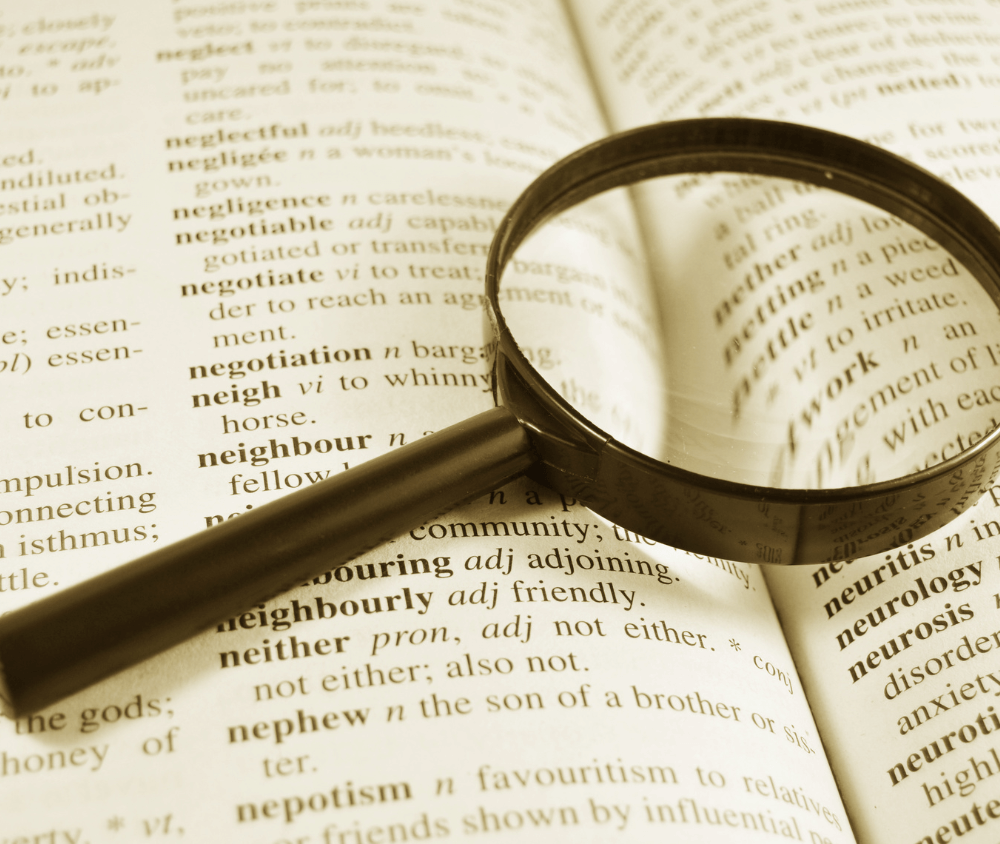 Magnifying glass over a dictionary searching for bookish meaning