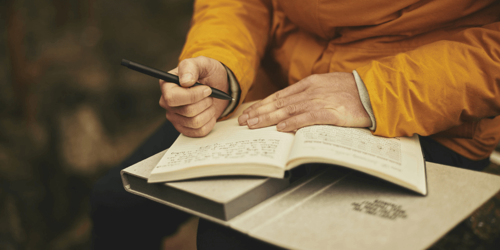 Person wearing yellow shirt writing in a journal