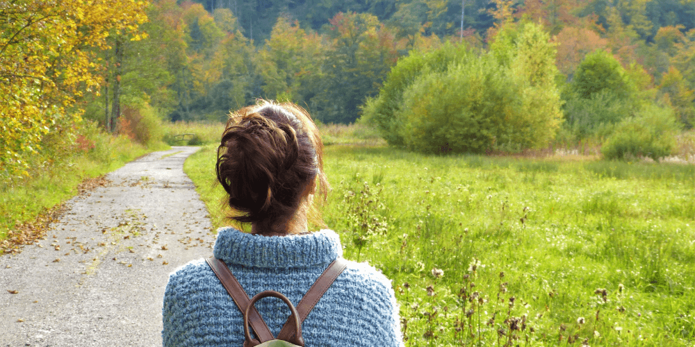 woman in a blue sweater and a backpack going on a nature walk