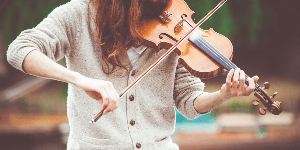 woman in a grey cardigan playing a violin